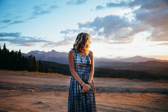 Woman in a tie-dye dress at sunset with mountains