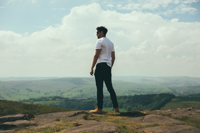 Man on a rocky outcrop overlooking a green valley