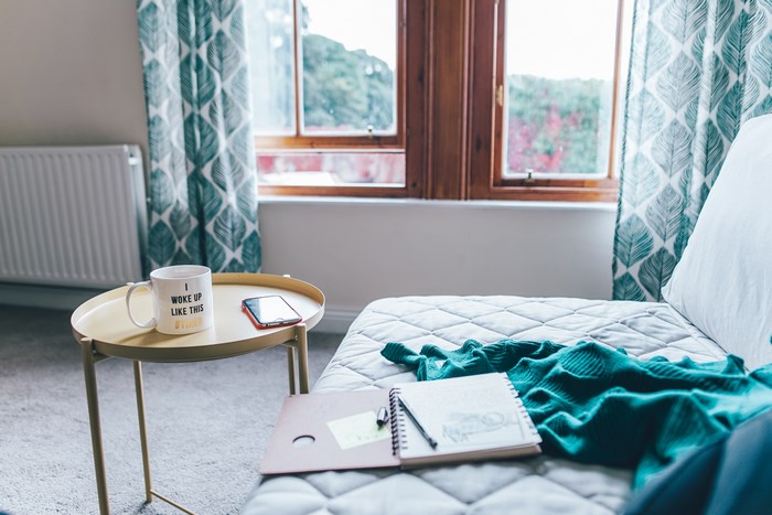 Mug, phone, and notebook on a table next to a couch