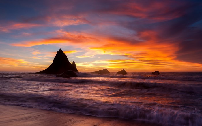 Sunset over the ocean with rock formations at Martins Beach