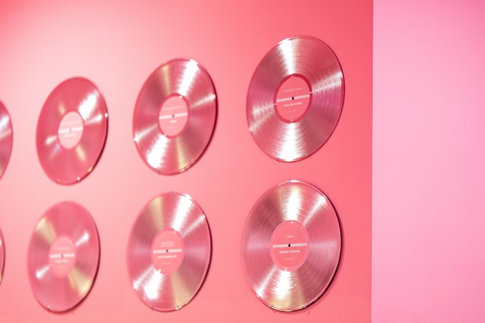 Pink vinyl records displayed on a pink wall