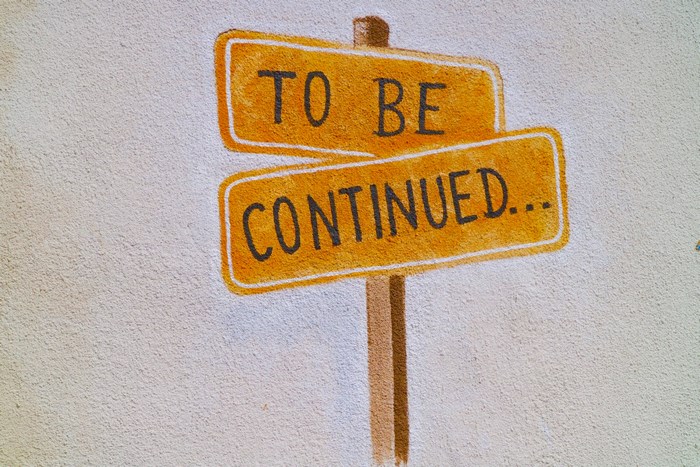Yellow signs with "TO BE CONTINUED" text on a wall