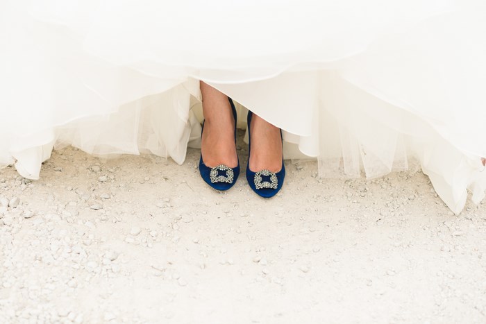 Bride's blue wedding shoes under a white dress