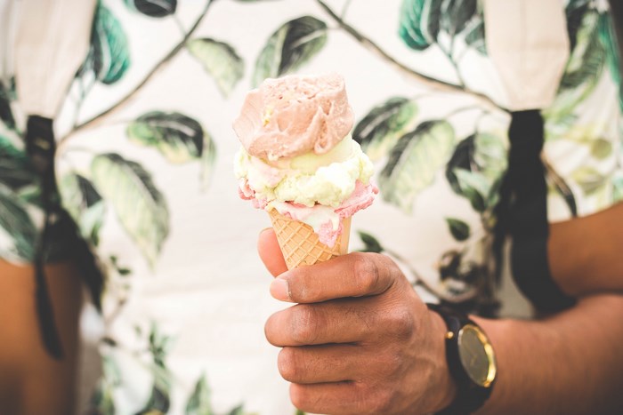 Person holding a melting ice cream cone with two scoops