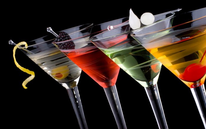 Four colorful cocktails with garnishes on black background