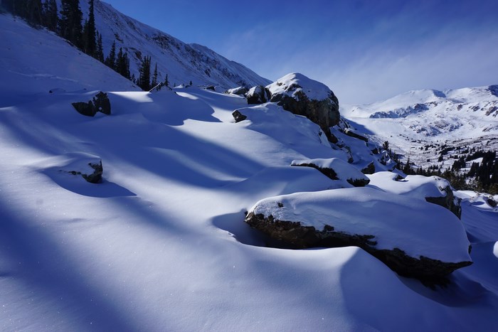 Snowy mountain range with rocks and trees