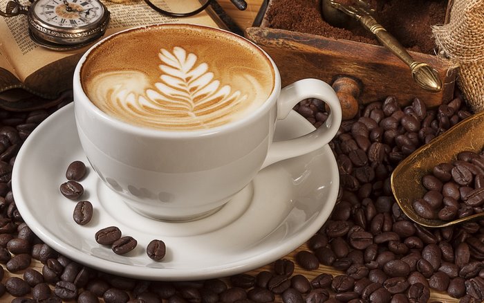 Latte art coffee cup with coffee beans and vintage pocket watch