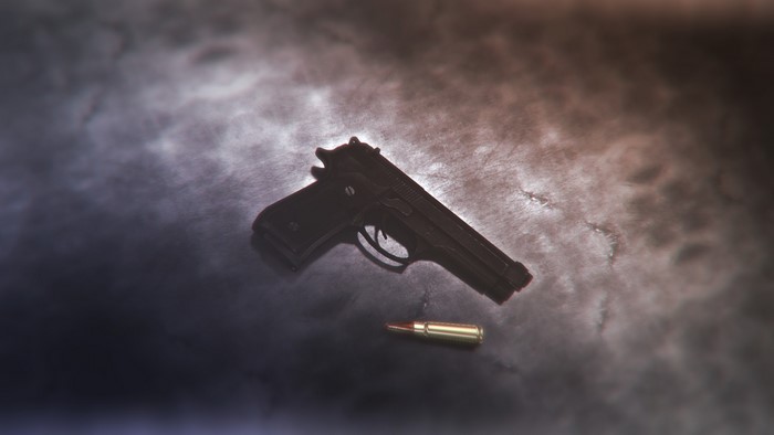 Pistol and bullet on a textured surface