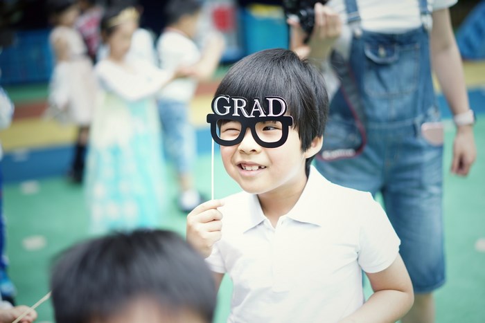 Boy wearing GRAD glasses at a graduation event