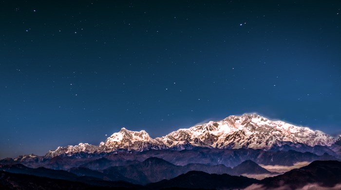 Snow-capped mountains under a starry night sky