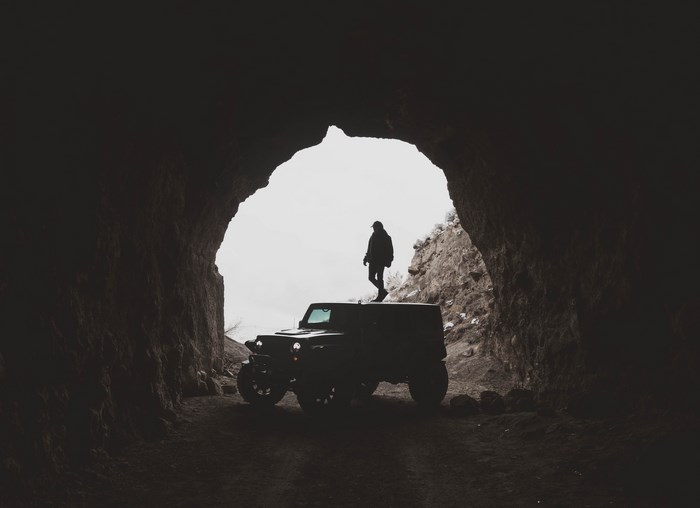 Man standing on a Jeep in a cave entrance