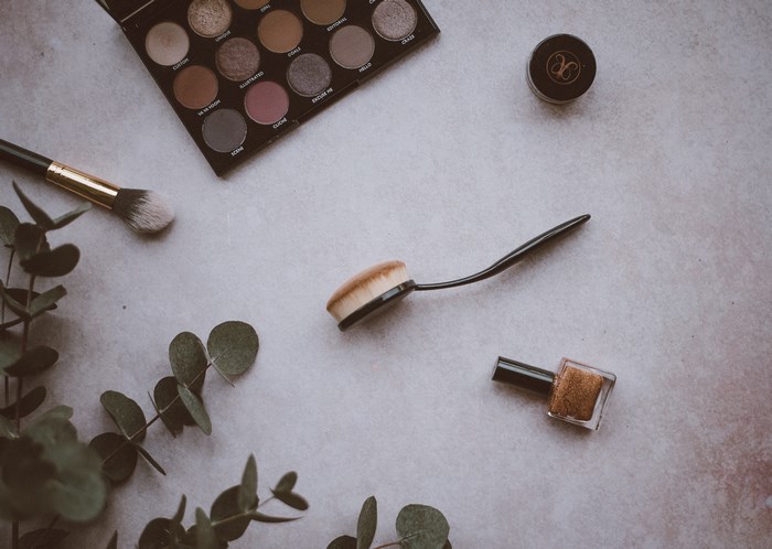 Flatlay of makeup products and eucalyptus leaves