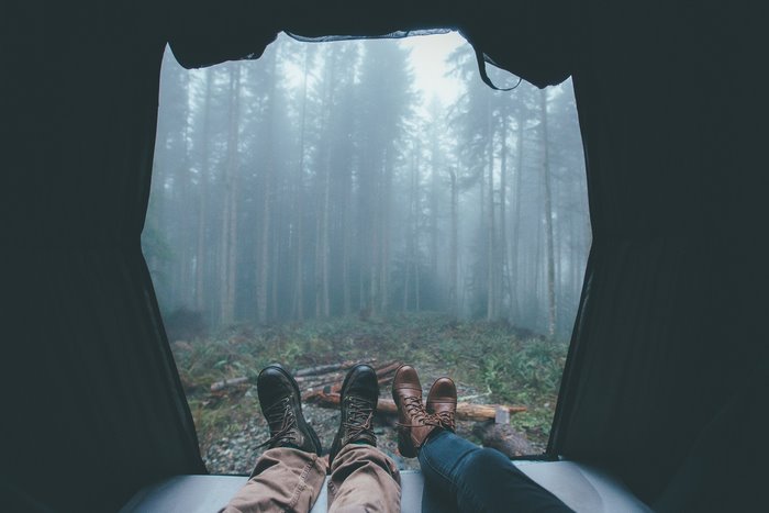 Couple relaxing in a tent in a foggy forest
