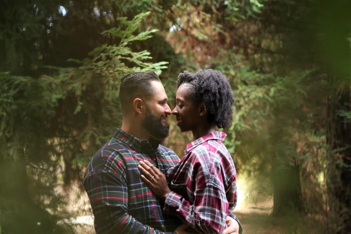 Biracial couple embracing in a forest