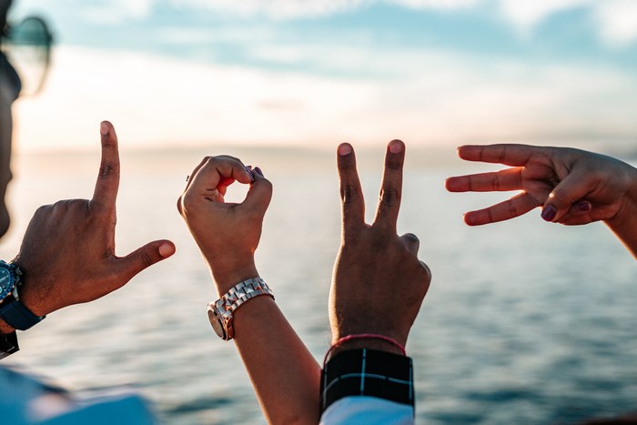 Hands forming the word LOVE with the ocean in the background