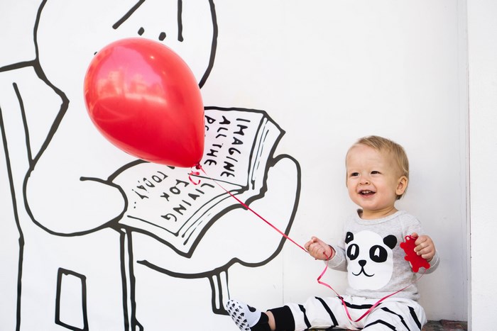 Happy toddler boy with red balloon and panda outfit