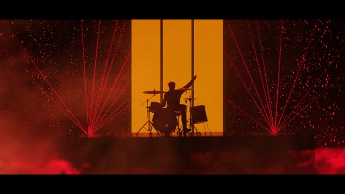 Drummer performing on stage with red lasers