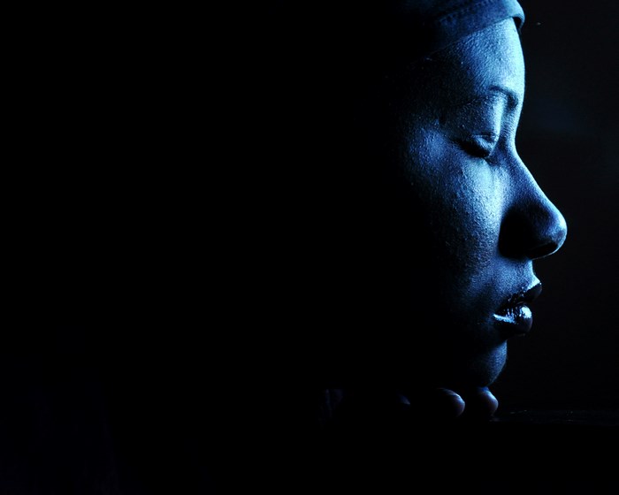 Woman's face illuminated by blue light in the dark
