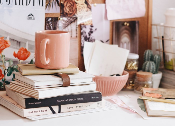 Pink mug on stack of books with desk accessories