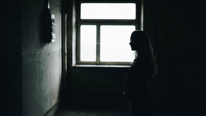 Silhouette of a woman standing by a window