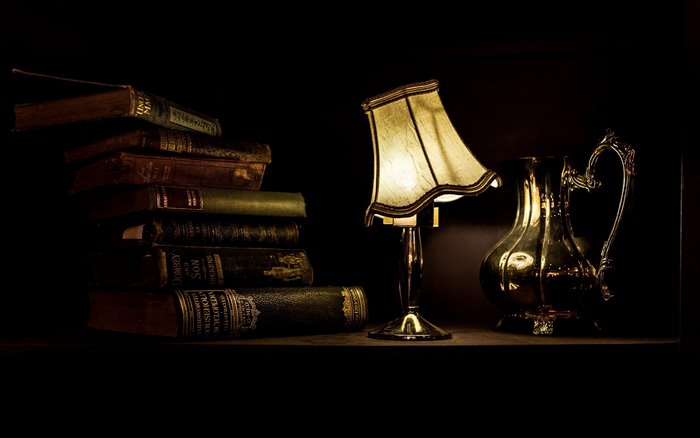 Stack of antique books with a lamp and pitcher