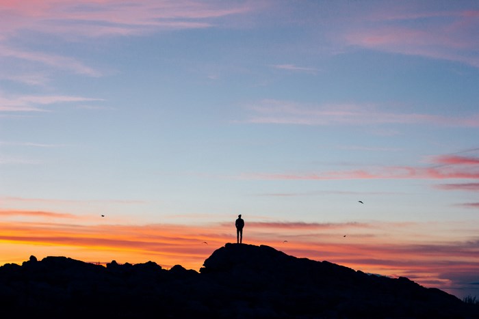 Silhouette of a person on a hill at sunset
