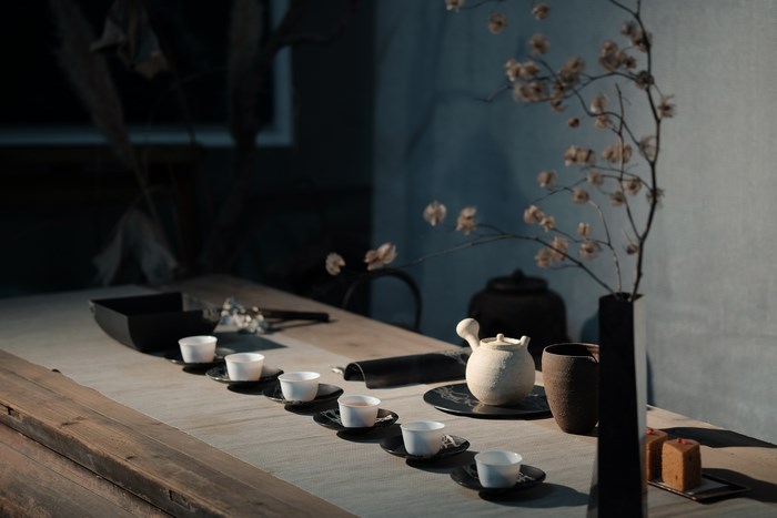Tea ceremony setup with cups, teapot, and dried flowers
