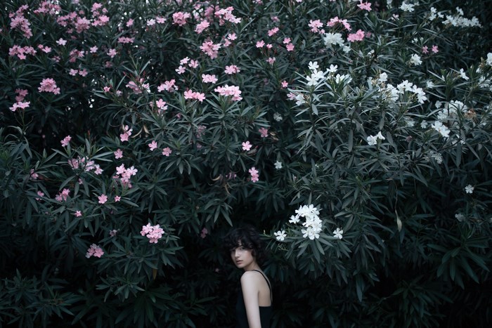 Woman hiding behind pink and white flowers