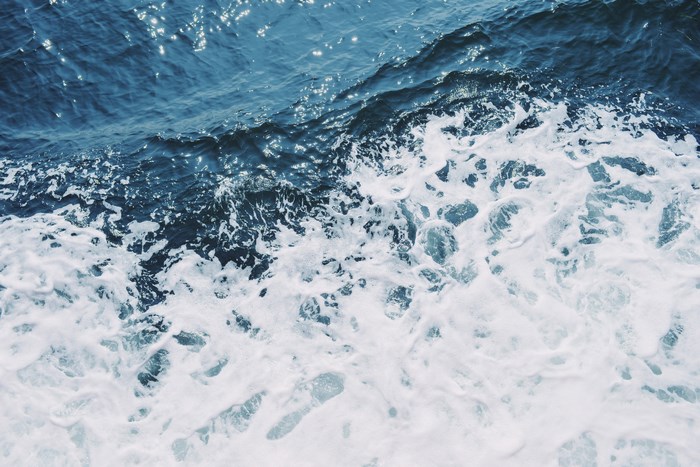 Blue ocean water with white foam and ripples