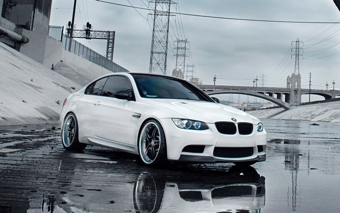 White BMW M3 with custom wheels in a concrete riverbed