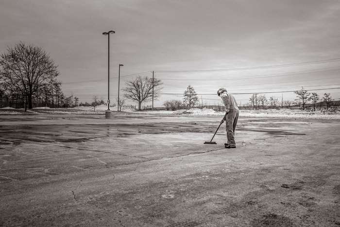 Man sweeping an empty parking lot in black and white 4K