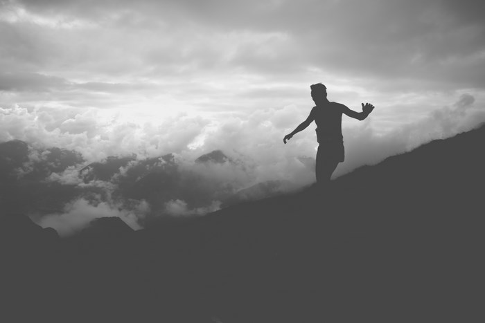 Silhouette of a man running on a cloudy mountain ridge