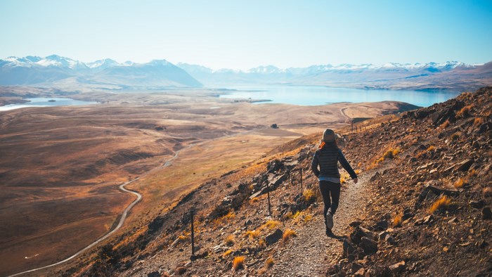 Woman hiking on a mountain trail overlooking a lake and mountains
