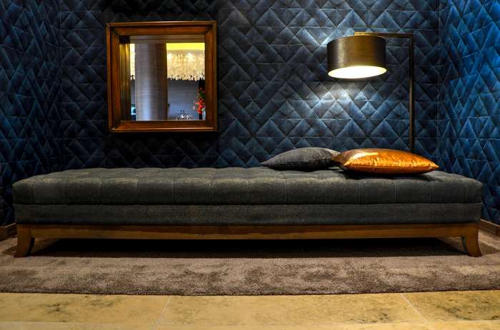 Tufted bench with pillows and floor lamp in a hotel room