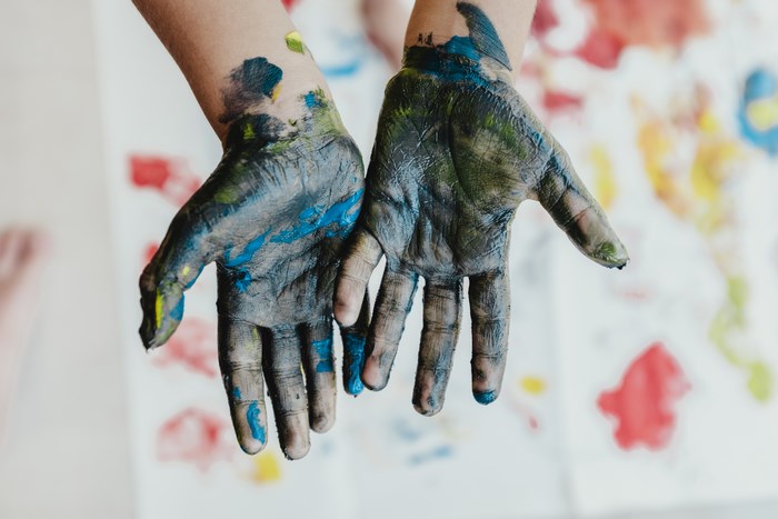 Child's hands covered in colorful paint