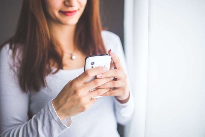 Woman in white shirt holding a smartphone