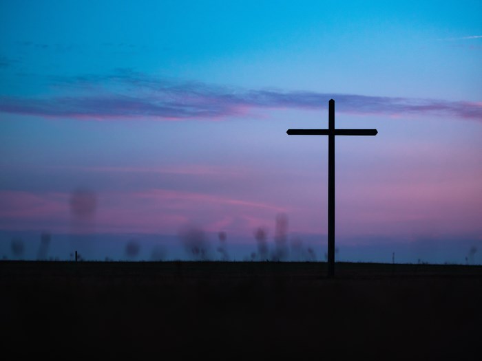 Silhouette of a cross against a colorful sunset sky