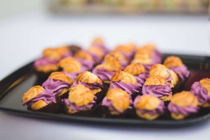 Purple cream-filled pastries on a black tray