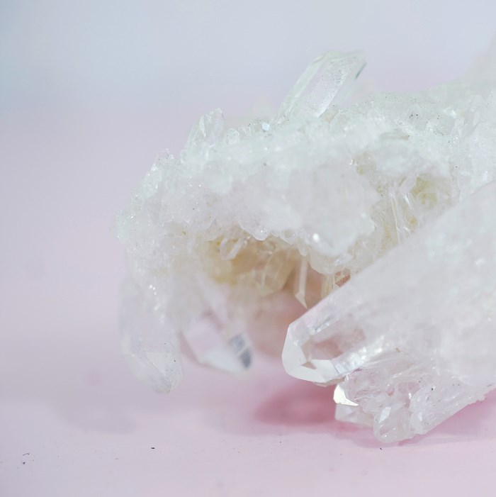 Close up of white quartz crystals on pink background