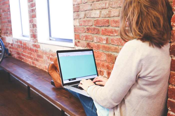 Woman working on a MacBook on a wooden bench