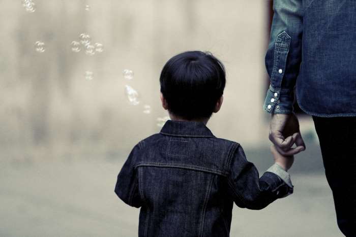 Child holding parent's hand with bubbles