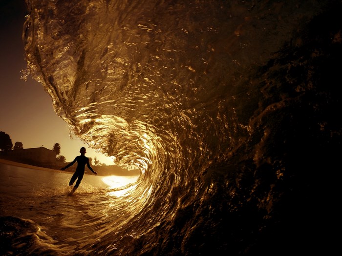 Surfer inside a golden wave at sunset