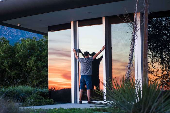 Man opening glass doors at sunset