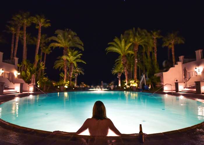 Woman relaxing in a swimming pool at night with palm trees