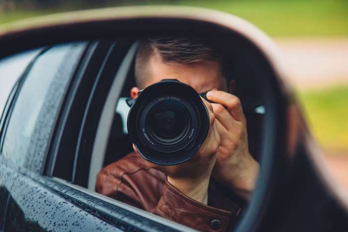 Man in car taking photo with DSLR camera
