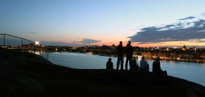 Silhouettes of people on a hill overlooking a city at dusk