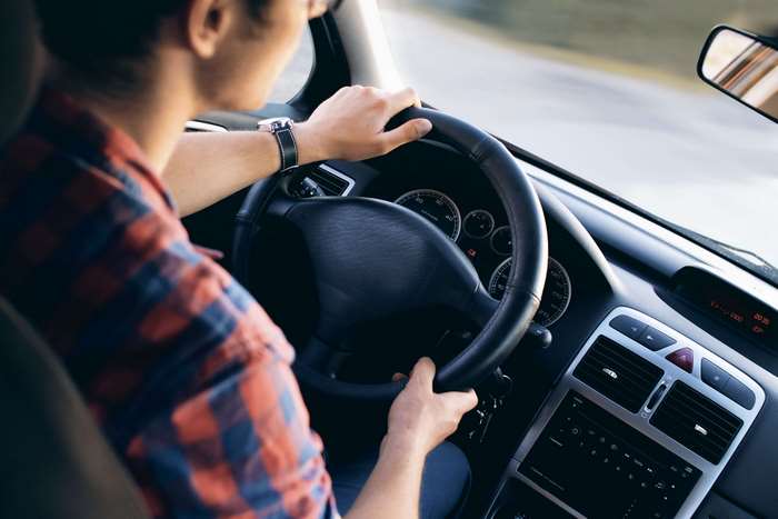 Man driving a car, close-up on steering wheel and dashboard
