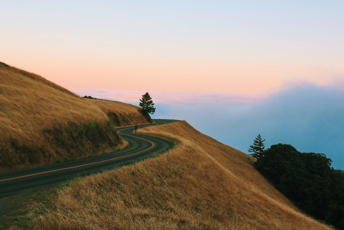 Winding mountain road at sunset with clouds