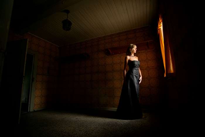 Woman in black dress in dark room near window