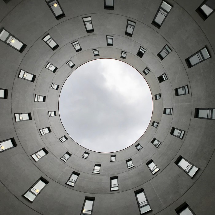 Concentric circles of windows in a building looking up at the sky